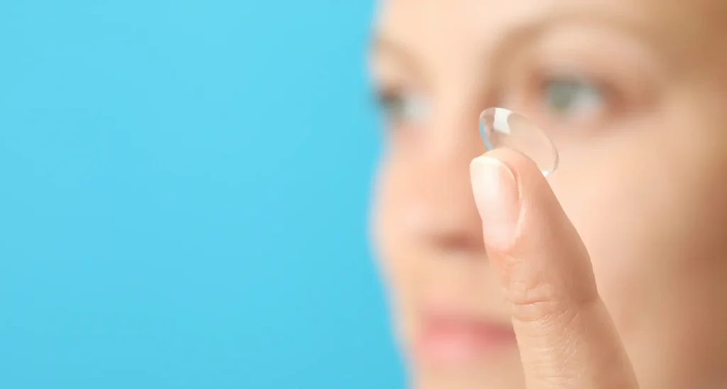 Mujer desenfocada sosteniendo un lente de contacto transparente frente a su rostro