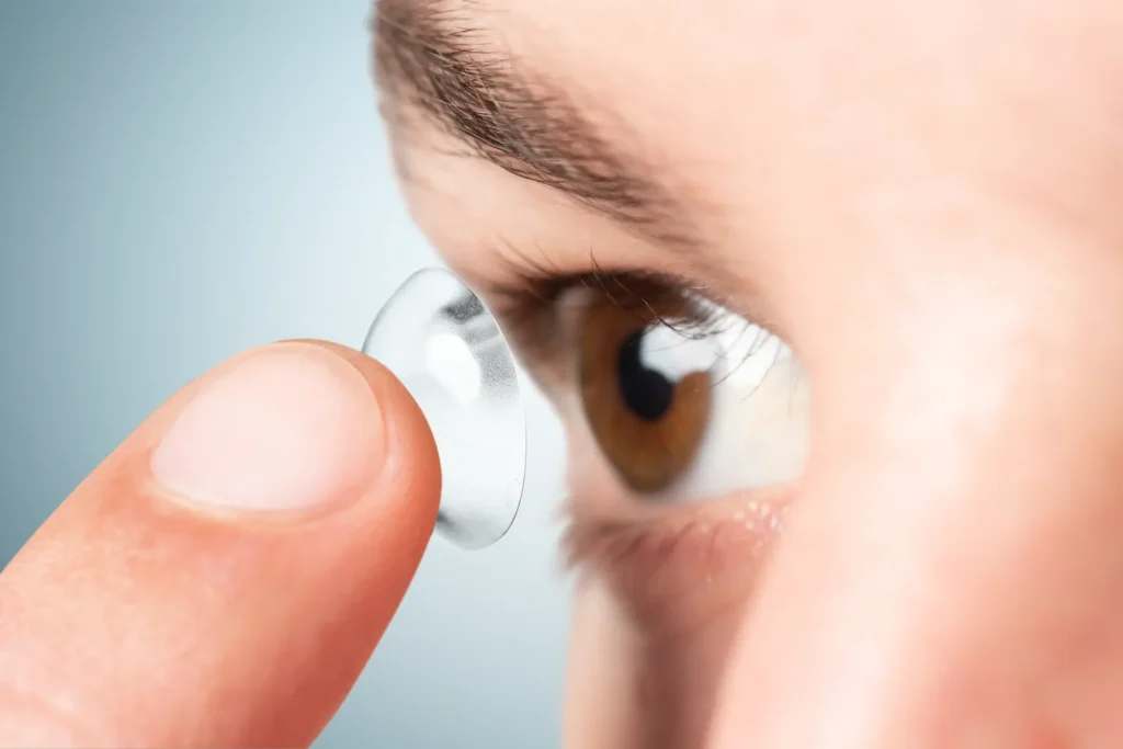 Primer plano de ojo marrón mientras se coloca un lente de contacto.