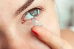 Mujer colocando un lente de contacto transparente en su ojo azul