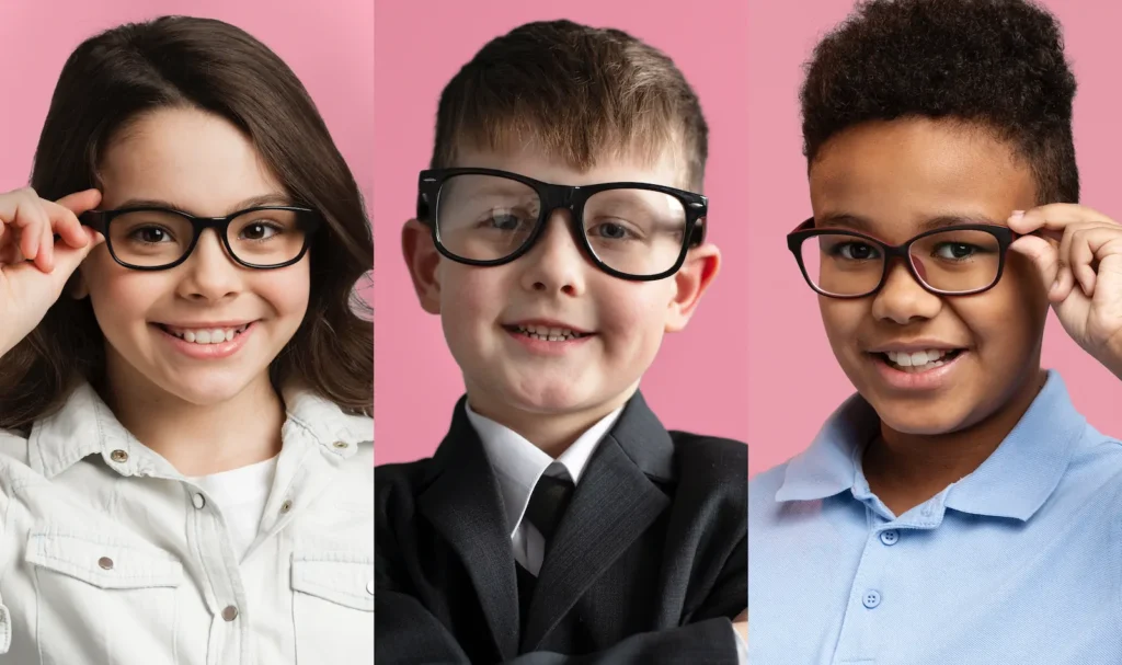 Niño con traje y lentes sonriendo frente a fondo rosa.