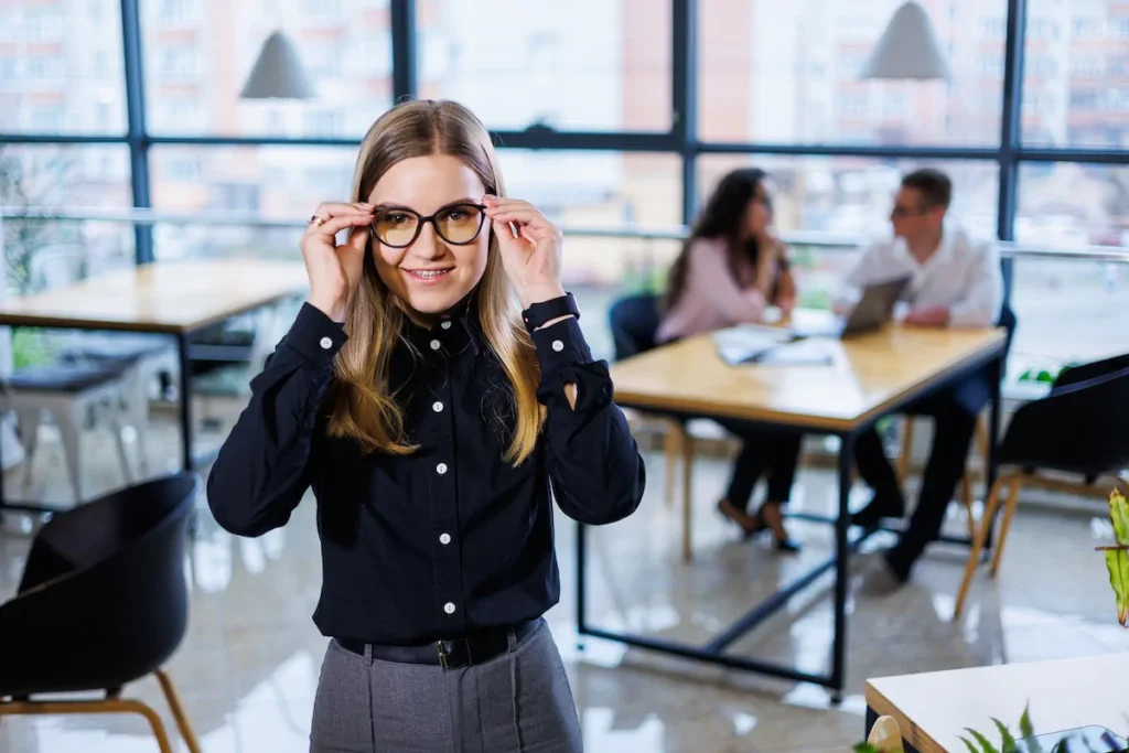 Mujer en oficina ajustando sus lentes antes de comenzar una reunión.