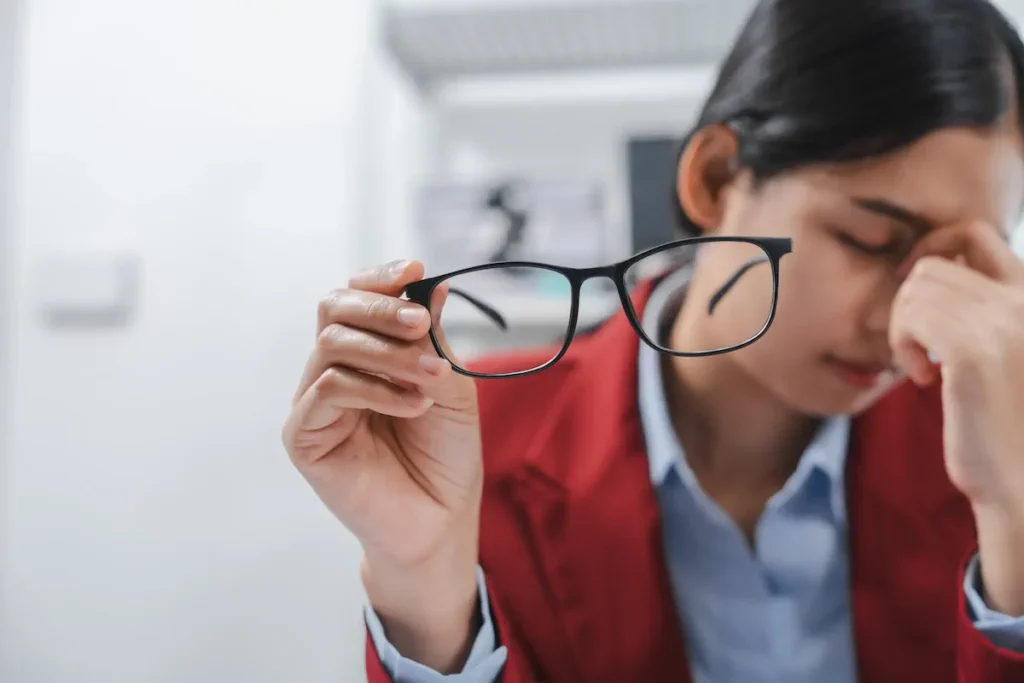 Persona revisando cuidadosamente unos lentes para detectar suciedad o daños.
