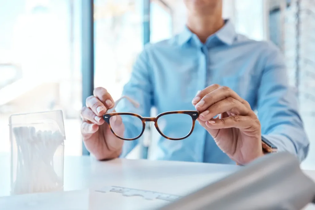 Persona sosteniendo unos lentes sobre una mesa con documentos y gráficos.