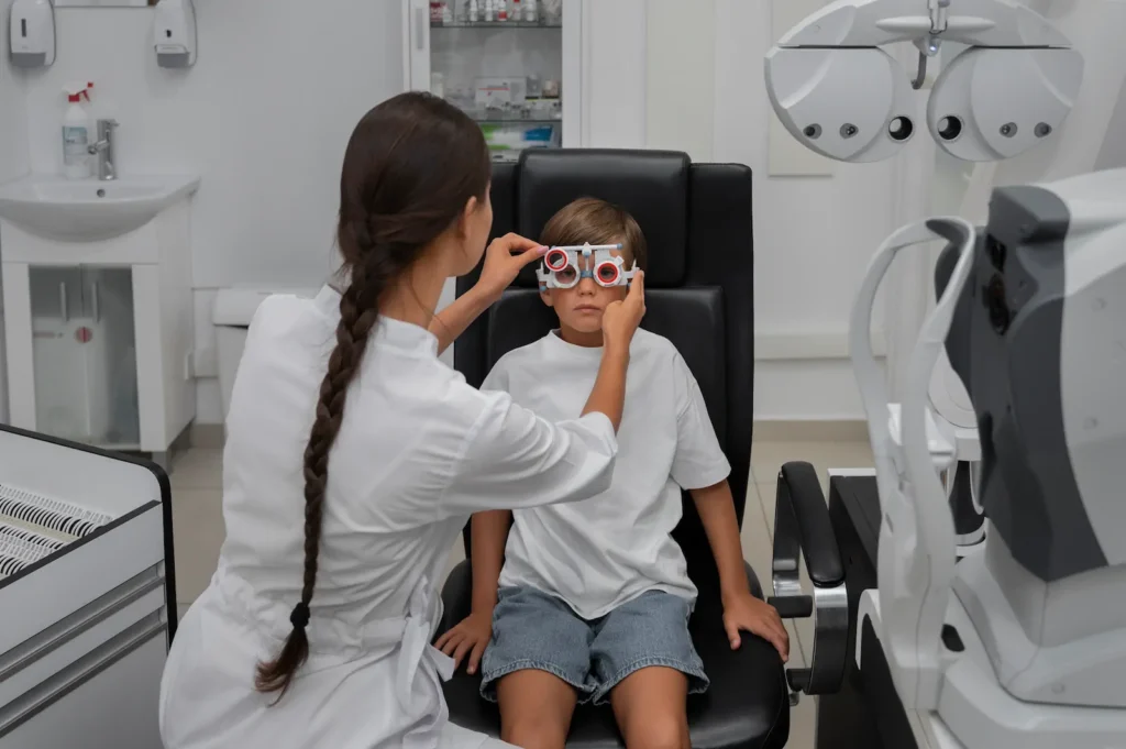 Optometrista realizando prueba visual a niño sentado en sillón durante examen de la vista infantil.