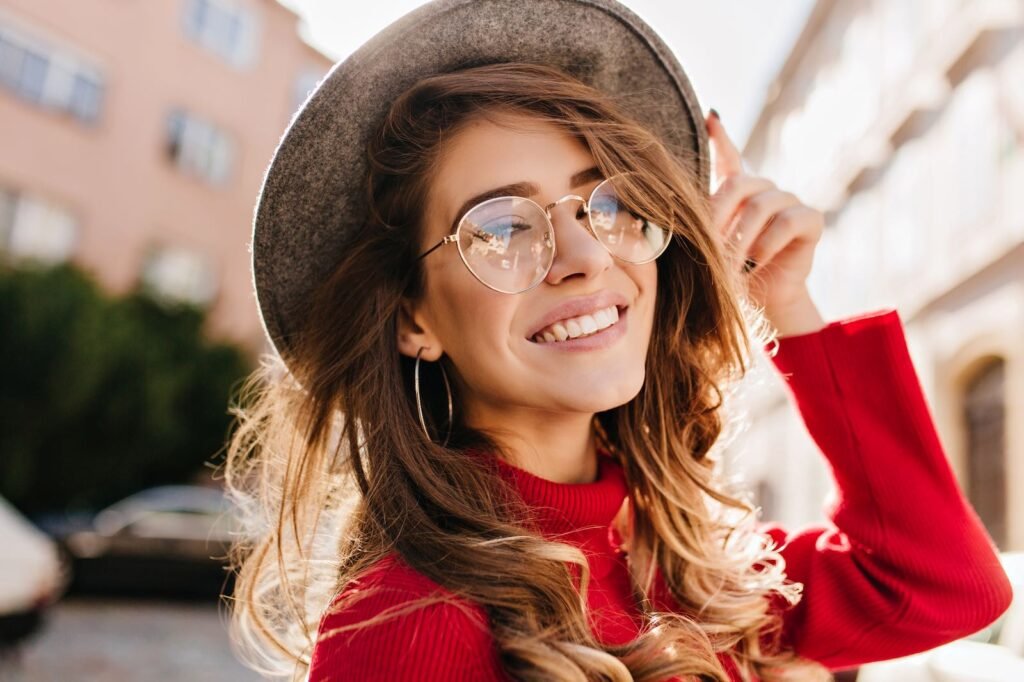 Mujer sonriendo con lentes graduados y sombrero en exterior