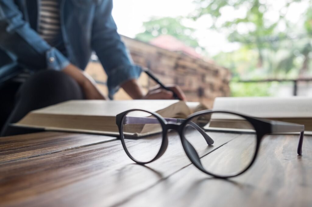 Lentes graduados sobre una mesa de trabajo junto a una libreta en un entorno profesional