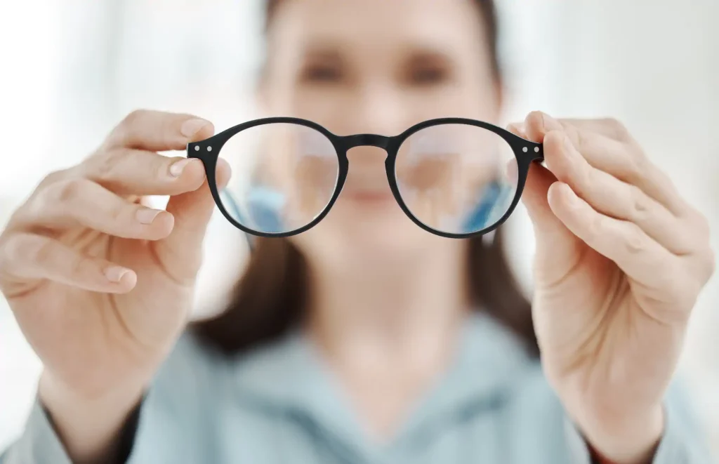 Mujer sosteniendo lentes frente a su rostro