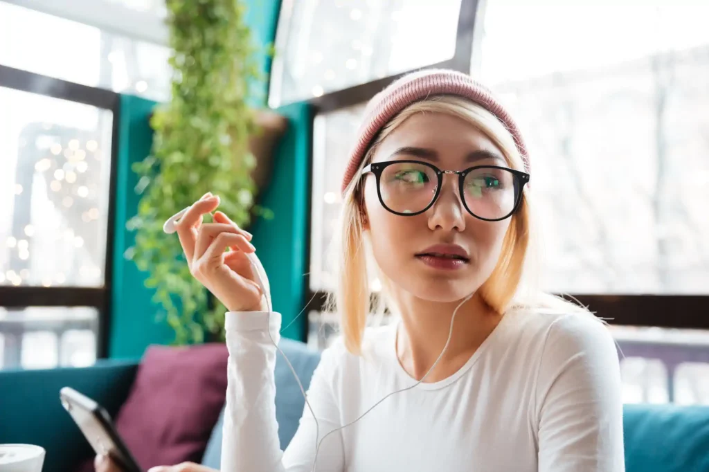 Mujer con lentes usando audífonos en cafetería