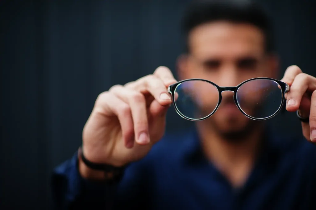 Hombre sosteniendo lentes frente a la cámara