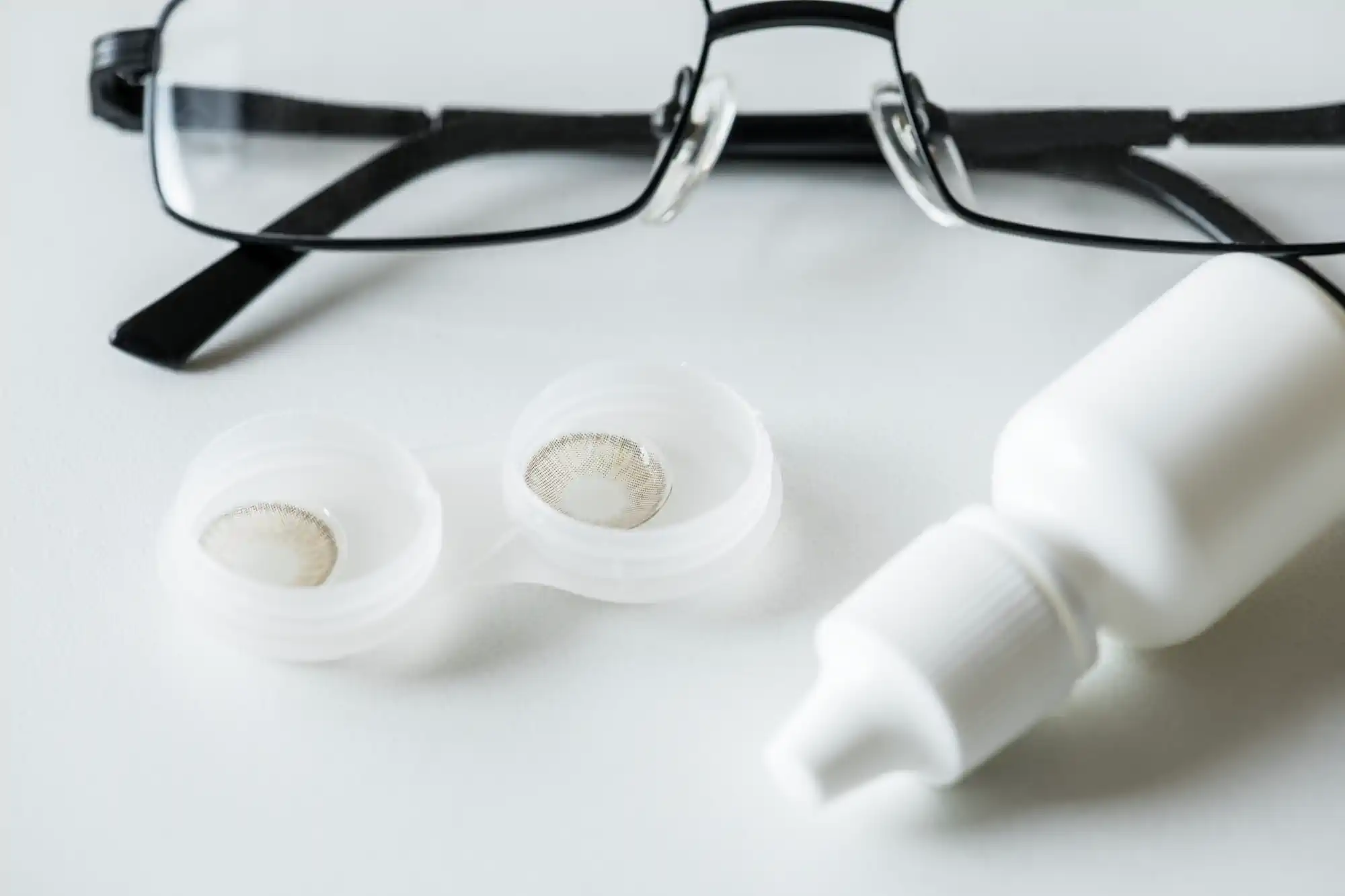 Lentes de contacto, estuche y gafas sobre mesa