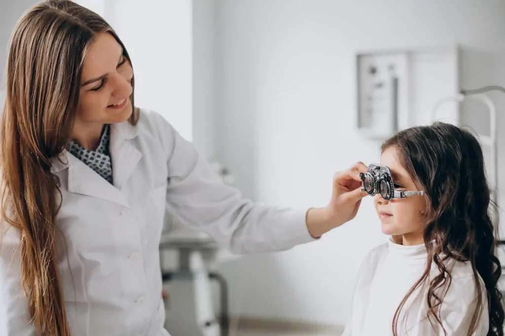 Optometrista examinando vista de niña con foróptero